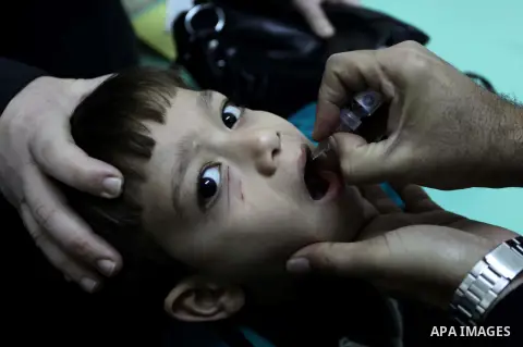 A Palestinian health worker administrates polio-vaccine drops to a child during five days of an anti-polio campaign, in Gaza City on December 09, 2013. The Minister of Health in Gaza Strip, Mufid al-Mokhalalaty, said on...