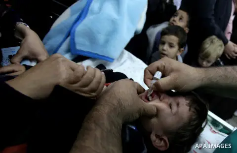 A Palestinian health worker administrates polio-vaccine drops to a child during five days of an anti-polio campaign, in Gaza City on December 09, 2013. The Minister of Health in Gaza Strip, Mufid al-Mokhalalaty, said on...