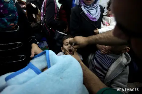 A Palestinian health worker administrates polio-vaccine drops to a child during five days of an anti-polio campaign, in Gaza City on December 09, 2013. The Minister of Health in Gaza Strip, Mufid al-Mokhalalaty, said on...