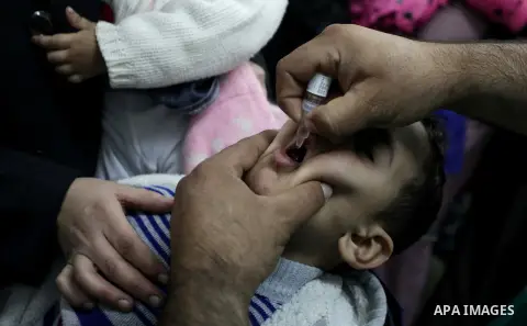 A Palestinian health worker administrates polio-vaccine drops to a child during five days of an anti-polio campaign, in Gaza City on December 09, 2013. The Minister of Health in Gaza Strip, Mufid al-Mokhalalaty, said on...