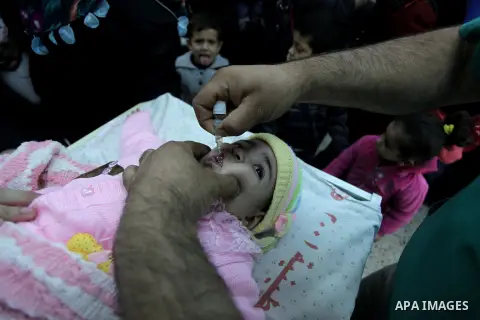 A Palestinian health worker administrates polio-vaccine drops to a child during five days of an anti-polio campaign, in Gaza City on December 09, 2013. The Minister of Health in Gaza Strip, Mufid al-Mokhalalaty, said on...
