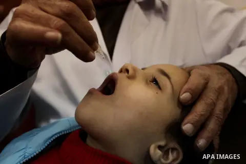 A Palestinian health worker administrates polio-vaccine drops to a child during five days of an anti-polio campaign, in Gaza City on December 09, 2013. The Minister of Health in Gaza Strip, Mufid al-Mokhalalaty, said on...