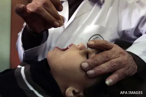 A Palestinian health worker administrates polio-vaccine drops to a child during five days of an anti-polio campaign, in Gaza City on December 09, 2013. The Minister of Health in Gaza Strip, Mufid al-Mokhalalaty, said on...