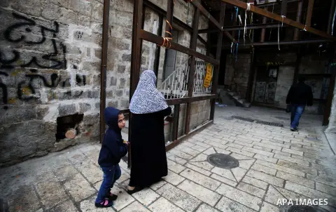A Palestinian man and her son walk at al-Qarmi neighborhood of Jerusalem's Old City, on December 10, 2013. Officials warned residents of the neighborhood to stay in their homes, that mainly cracked due to the excavations...