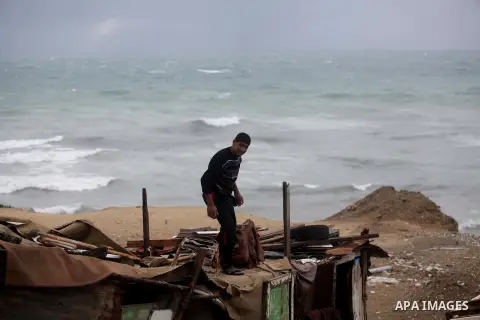 A Palestinian youth work on his tent at the beach during heavy rains on a stormy day in Gaza City, December 11, 2013. The Gaza Strip Power Authority is worried that electricity will be available for less than six hours a...