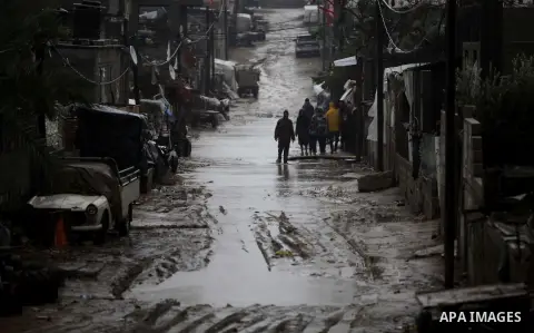 Palestinians walk in a flooded street during heavy rains on a stormy day in Gaza City, December 11, 2013. The Gaza Strip Power Authority is worried that electricity will be available for less than six hours a day in Gaza...