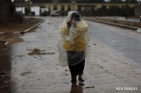 A Palestinian woman covers her body with a plastic sheet on her way to her house during heavy rains on a stormy day in Gaza City, December 11, 2013. The Gaza Strip Power Authority is worried that electricity will be avai...
