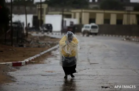 A Palestinian woman covers her body with a plastic sheet on her way to her house during heavy rains on a stormy day in Gaza City, December 11, 2013. The Gaza Strip Power Authority is worried that electricity will be avai...