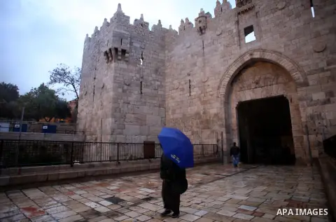 Palestinians walk in front of Damascus gate during heavy rains on a stormy day in Jerusalem's old city, December 11, 2013. Photo by Saeed Qaq