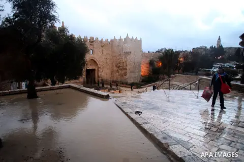 Palestinians walk in front of Damascus gate during heavy rains on a stormy day in Jerusalem's old city, December 11, 2013. Photo by Saeed Qaq