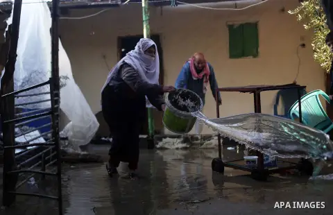 A Palestinian woman scoops floodwater from her house on a stormy day in Dir al-Balah in the central Gaza Strip December 13, 2013. A severe winter deluge enveloping much of the Eastern Mediterranean added to the woes of P...