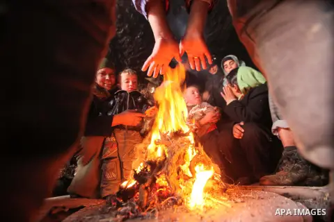 A Palestinian family gather around fire as they get themselves warm inside a cave where they live in the West Bank village of al-Mufaqara, south of Hebron, on December 13, 2013. The hilltop city of Jerusalem was paralyse...
