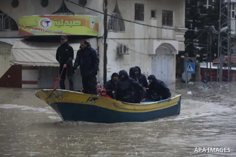 Palestinian civil defense members help people to transfer on a boat after their houses were flooded in Gaza city on Dec. 14, 2013 as a severe winter deluge hit the region. Photo by Ashraf Amra