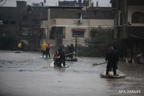 Palestinian civil defense members help people to transfer on a boat after their houses were flooded in Gaza city on Dec. 14, 2013 as a severe winter deluge hit the region. Photo by Ashraf Amra