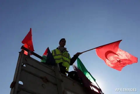 A Palestinian civil defense volunteer waves a Turkish flag in flood waters in Gaza City following rain storms for the past few days, on December 15, 2013. More than 5,000 people have been evacuated from flood-damaged hom...