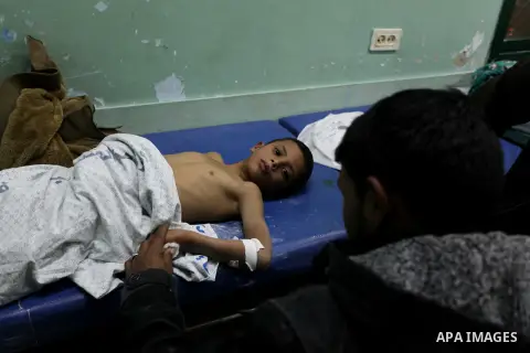 Palestinians gather arround a child, who medics said was wounded by shrapnel during an Israeli air strike on Al Maghazi camp, at treatment room of Al-Aqsa hospital in Deir Al Balah, central Gaza Strip, Tuesday, Dec. 24,...