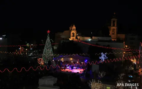 Christians take part in the Christmas celebrations outside the Church of the Nativity in the West Bank city of Bethlehem, on December 24, 2013. Thousands of Palestinians and tourists flocked into the West Bank city of Be...