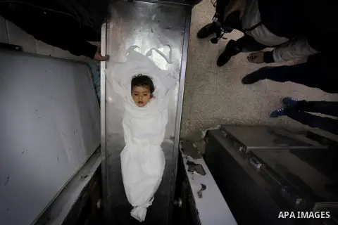 Palestinians gather arround the body of three-year-old Palestinian girl Hala Abu Sabikha in the morgue of a hospital in Deir al-Balah, in the central Gaza Strip, on December 24, 2013. Sabikha was killed and at least six...