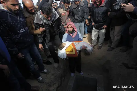 A relative carries the body of three-year-old Hala Abu Sabakha during her funeral in the central of Gaza Strip, on December 25, 2013. Sabikha was killed and at least six other people wounded in a series of Israeli air an...