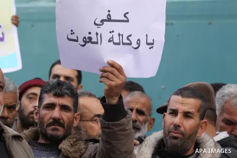 Palestinians hold banners during a protest against the UNRWA decision to reduce of the work contracts in front of the headquarters United Nations Relief and Works Agency (UNRWA) in Gaza city, on Dec. 26, 2013. Photo by M...
