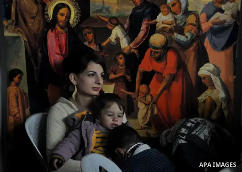 A Palestinian christian woman hugs her sons during the celebration of the New Year at the Church of Saint Porphyrius, in Gaza City, December 31, 2013. Photo by Mohammed Talatene