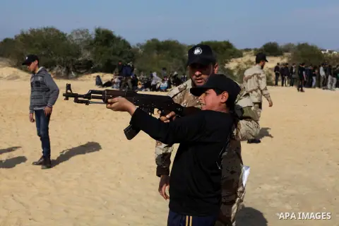 A member of Palestinian security forces teaches a Palestinian high school student how to use a weapon during a military-styled exercise routine at a course conducted by the Hamas-run ministry of education, in Rafah in th...