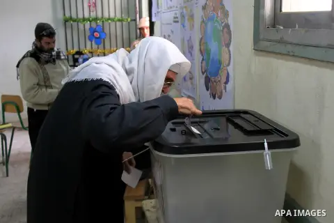 An Egyptian polling station staff member looks on as a woman fills her ballot paper, during the referendum on the draft constitution, inside a polling station in Cairo, Egypt, 14 January 2014. Egyptians began on 14 Janua...