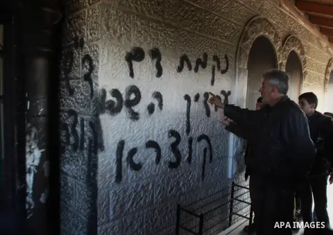 Palestinians inspect the entrance to of a mosque scrawled with graffiti that reads in Hebrew, "Arabs out" and "Revenge for blood spilled in Qusra" in the West Bank village of Deir Istiya which lies next to the sprawling...