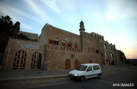 A picture taken on January 15, 2014 shows a man ride his car past the mosque of sea, near the Jaffa seaport. Photo by Saeed Qaq