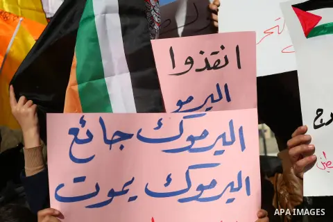Palestinian protesters wave national and Democratic Front for the Liberation of Palestine flags and hold placards during a demonstration in solidarity with Palestinian refugees in Yarmouk refugee camp in the suburbs of t...