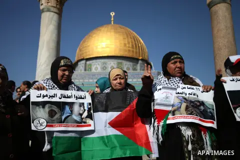 Palestinian worshipers hold placards during a protest in solidarity with Palestinian refugees in Yarmouk camp in Syria who are living in low conditions and under the siege, following Friday prayers at the Al-Aqsa compoun...