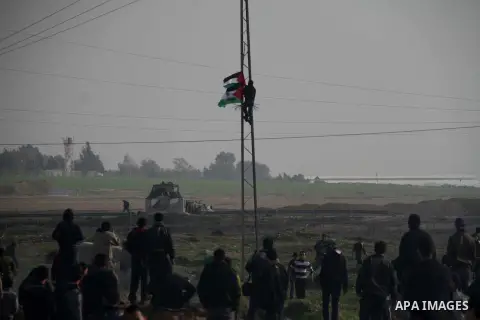 A Palestinian protester hangs his national flag on a column during clashes with Israeli forces near the Nahal Oz border crossing with Israel, east of Gaza City on January 17, 2014. The Israeli army fired live rounds and...