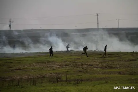 Palestinian protesters run away from tear gas fired by Israeli security forces during clashes near the Nahal Oz border crossing with Israel, east of Gaza City on January 17, 2014. The Israeli army fired live rounds and t...