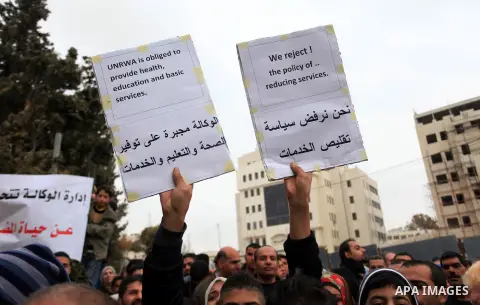 Palestinian employees hold placard during a protest demanding the United Nations Relief and Works Agency for Palestine Refugees (UNRWA), for more attention for their conflict with the UN agency, in the West Bank City of...
