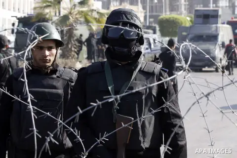 Police and security forces stand guard outside a police academy, where the trial of ousted Egyptian President Mohamed Mursi and members of the Muslim Brotherhood is due to take place, on the outskirts of Cairo, January 2...