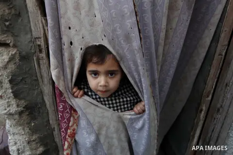 A Palestinian girl looks through a curtain as she plays in front her Family's house at al-Shati refugee camp in the west Gaza City January 29, 2014. Photo by Ashraf Amra