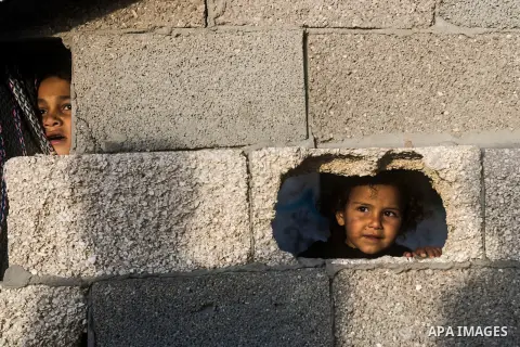 Palestinian children look through holes in a wall at their family's house at al-Shati refugee camp in the west Gaza City on January 30, 2014. Photo by Abdullah Jadallah