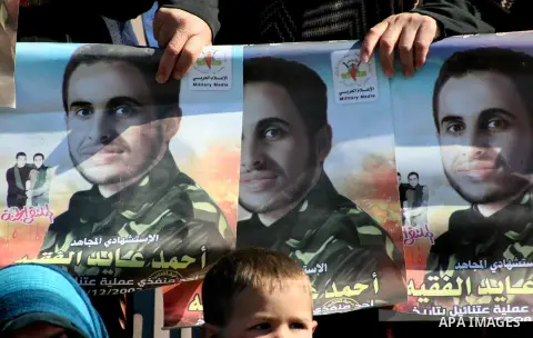 Palestinian women hold posters of Ahmed al-Faqih, during a funeral in the West Bank village of Dura, southeast of Hebron, Feb. 10, 2014. Israel on Sunday evening delivered the remains of Ahmad Ayid Faqih who was killed i...