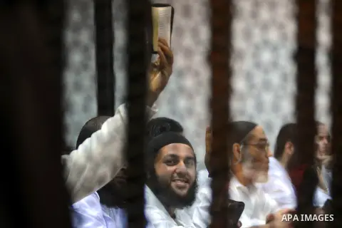 Egyptian suspects in the case of the 'Nasr City terrorist cell' look from inside the defendants cage during their trial, in Cairo on February 18, 2014. Cairo Criminal Court of the Supreme State Security postponed Tuesday...