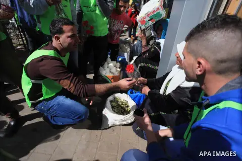 Palestinian youth distribute roses during a participate in the campaign " for the good, we gather" honoring for the elderly working women at the streets, in the West Bank city of Ramallah, on Feb. 22, 2014. Photo by Issa...