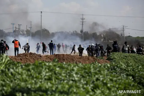 Palestinian protesters run seek for cover from tear gas fired by Israeli security forces during clashes near Nahal Oz border crossing with Israel, east of Gaza City, on February 25, 2014 following a demonstration to comm...