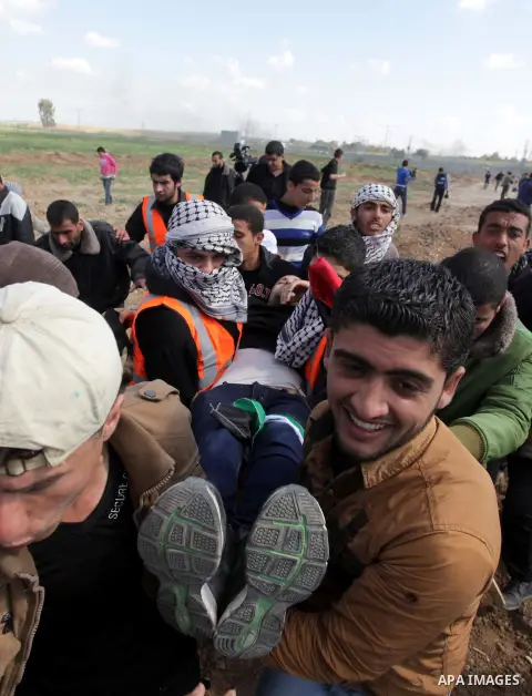 Palestinians carry an injured man during clashes with Israeli security forces near Nahal Oz border crossing with Israel, east of Gaza City, on February 25, 2014 following a demonstration to commemorate the Ibrahimi Mosqu...