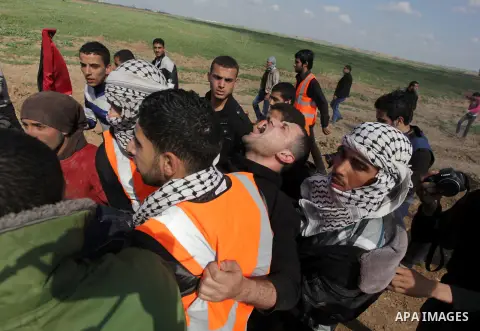 Palestinians carry an injured man during clashes with Israeli security forces near Nahal Oz border crossing with Israel, east of Gaza City, on February 25, 2014 following a demonstration to commemorate the Ibrahimi Mosqu...