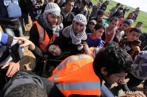 Palestinians carry an injured man during clashes with Israeli security forces near Nahal Oz border crossing with Israel, east of Gaza City, on February 25, 2014 following a demonstration to commemorate the Ibrahimi Mosqu...