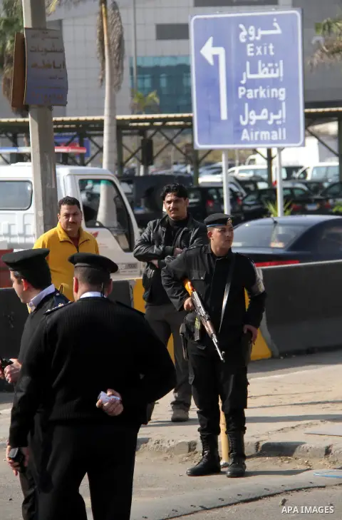 Egyptian security stand guard as ambulances drive out of Cairo international airport on February 26, 2014, carrying the bodies of seven Egyptian victims who were found shot dead in Jalluta, near Benghazi in eastern Libya...
