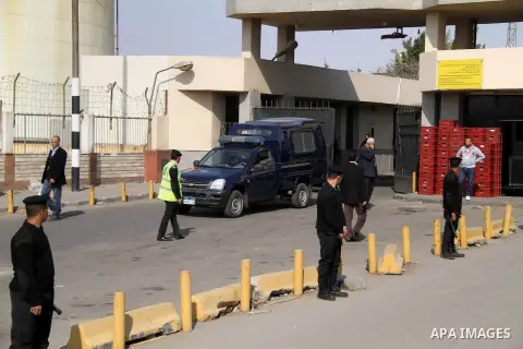 Egyptian security stand guard as ambulances drive out of Cairo international airport on February 26, 2014, carrying the bodies of seven Egyptian victims who were found shot dead in Jalluta, near Benghazi in eastern Libya...