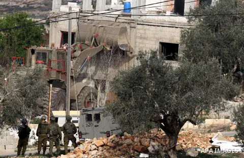 Israeli soldiers stand guard as an army bulldozer demolishes the house of Palestinian Moataz Washaha, who died during an Israeli army raid on his home in the northern West Bank town of Bir Zeit, near Ramallah on February...