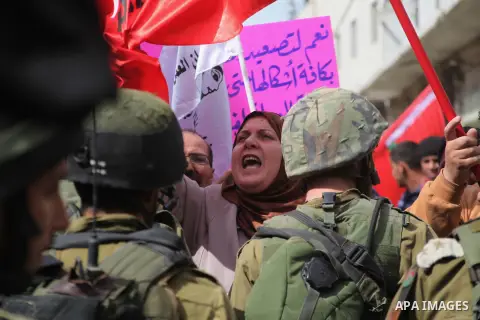 Israeli security forces stand guard as Palestinian protestors hold banner and shout slogans against Israeli settlements and calling for the opening of Hebron's main Shuhada street and a boycott on all products made in th...