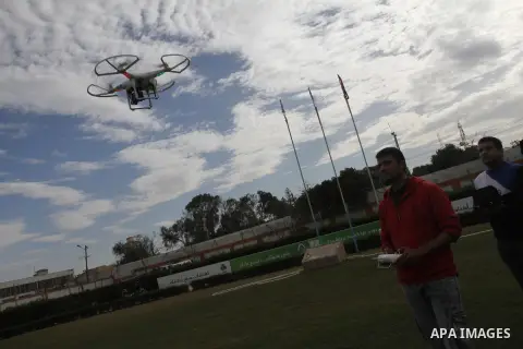 Palestinian youths control by remote control the drone plane with a camera during a test at al Yarmouk Stadium in Gaza city, on March 1, 2014. Palestinian company "Media Town" imported a drone plane is dedicated to film...