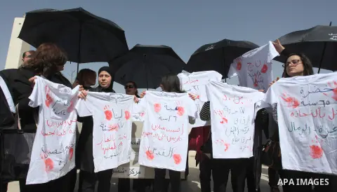 Palestinian women hold up T-shirts with red hand prints and slogans as they protest against so-called honour killing in which over two dozen women were murdered in 2013 according to the Palestinian Ministry of Women s Af...